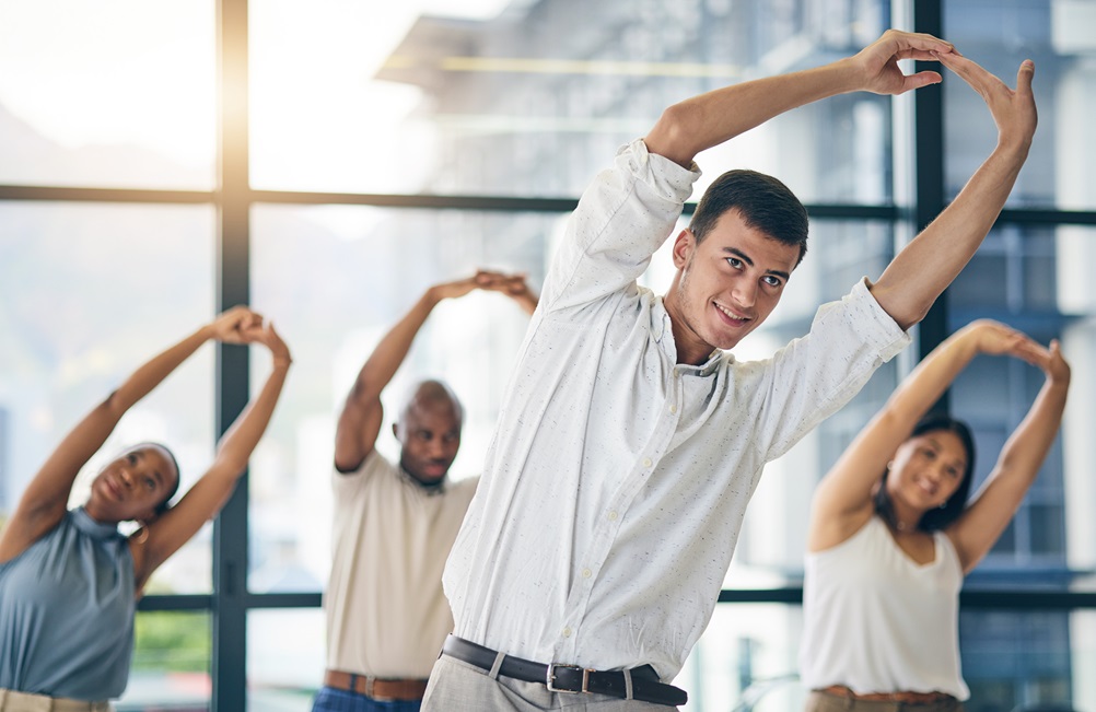 Pessoas em escritório praticando ginástica laboral para o saúde laboral.